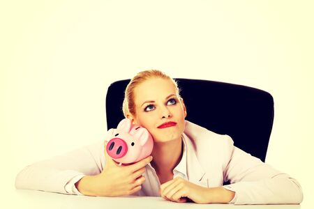Happy business woman with a piggybank behind the desk.の写真素材
