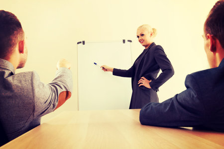 Smiling businesswoman drawing a graph for her colleagues on the whiteboard.