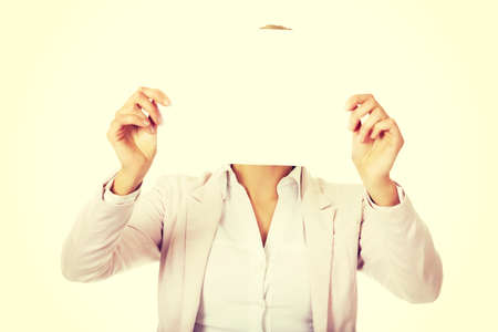 Business woman covering face with blank paper sheet.の写真素材
