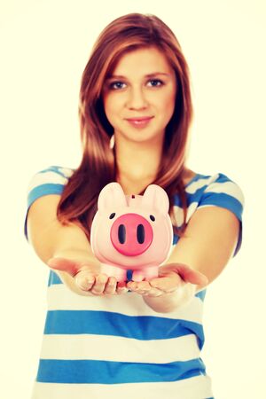 Happy teenage woman holding piggybank.の写真素材