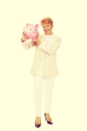 Smile elderly woman holding piggy bank.の写真素材