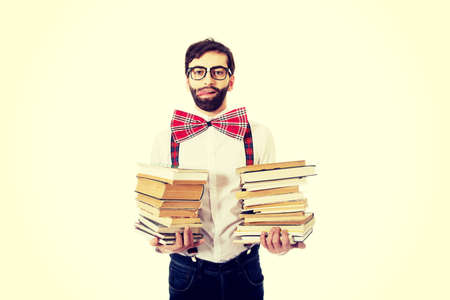 Handsome man wearing suspenders holding stack of books.の写真素材