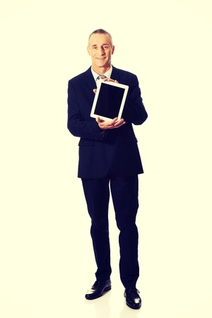 Smiling mature businessman holding digital tablet.の写真素材