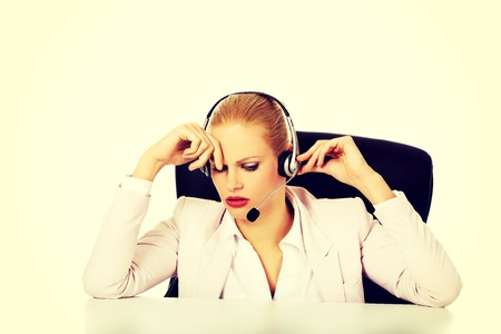 Young woman helpline operator is trying to hear something through a headphones.の写真素材