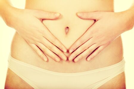 Woman is having heart shape made from hands on her belly.の写真素材