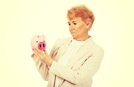 Pensive elderly woman holding piggy bank.の写真素材