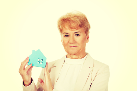 Smile elderly business woman holding blue paper house.の写真素材