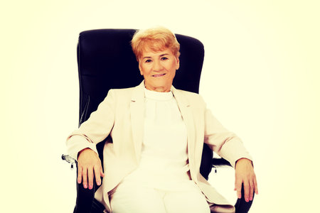 Smile elderly business woman sitting on armchair.の写真素材
