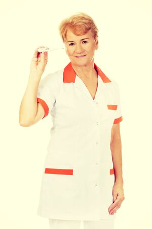 Smile elderly female doctor or nurse holding thermometer.の写真素材