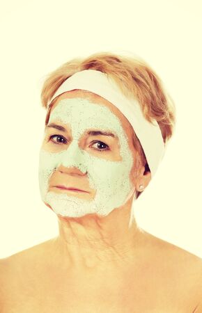 Relaxed elderly woman in facial mask.の写真素材