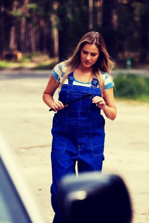 Female mechanic changing tire with wheel wrench.の写真素材