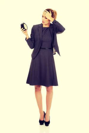 Worried business woman holding alarm clock.の写真素材