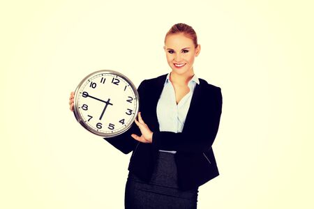 Smiling young business woman holding office clock.の写真素材