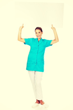 Young female doctor or nurse holding empty banner.の写真素材