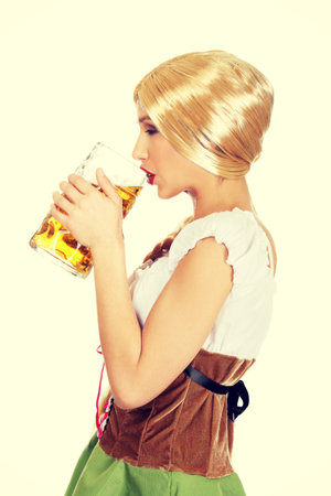 Young and beautiful bavarian woman drinking beer.の写真素材
