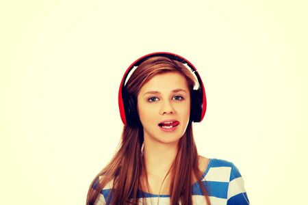 Teenage woman listens to music and shows tounge.の写真素材