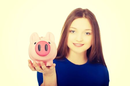 Happy teenage woman holding piggybank.の写真素材