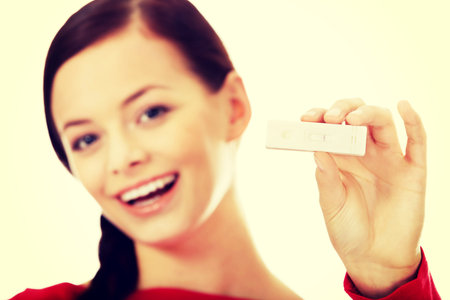 Happy young woman shows positive pregnancy test.
