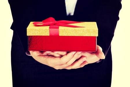 Woman holding christmas present with red bow.の写真素材