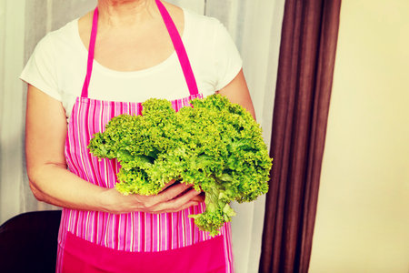 Senior woman holding green salad.の写真素材
