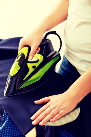 Young woman ironig man's jacket on ironing board.の写真素材