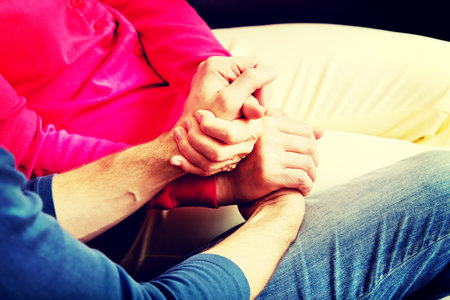Mother and son sitting on couch and holding hands.