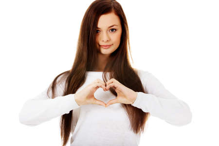 Beautiful young woman making a heart symbol with her hands.の写真素材