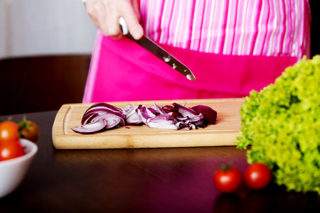 Woman cut red onion on cutting board.の写真素材
