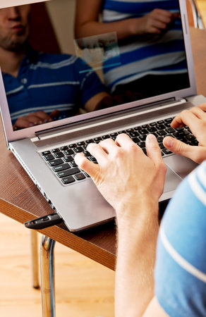 Young man sitting at the table and using laptop.