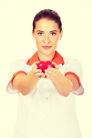 Young female doctor or nurse holding toy heart.の写真素材