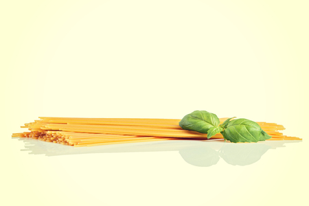 Uncooked dry fettuccine pasta  with green basil.の写真素材