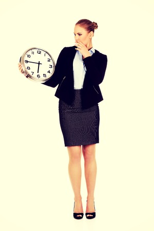 Yawning business woman holding office clock.の写真素材