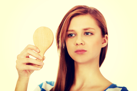Teenage beautiful woman looking in a mirror.の写真素材