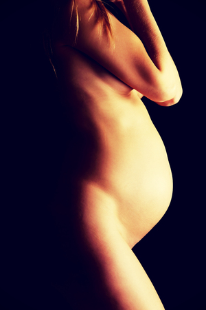 Woman touching her growing pregnant bellyの写真素材