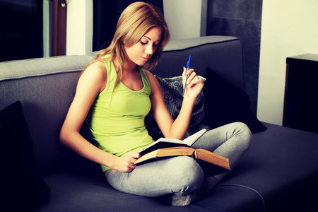Young teenage woman learning to exam on a sofa.