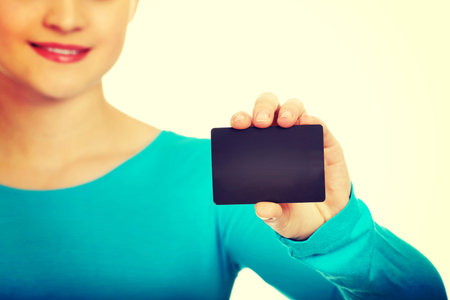 Happy teenage woman holding paper card.