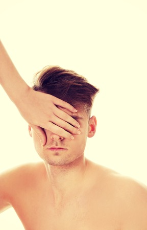 Woman's hand covering shirtless man's eyes.の写真素材