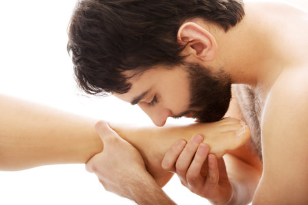 Handsome young man kissing woman's bare feet.の写真素材