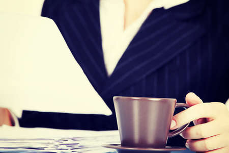 Working business woman with dociments and a cup of coffee or tea.の写真素材