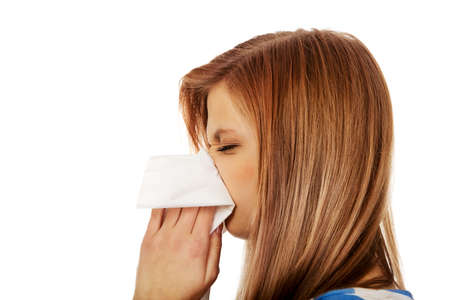 Teen woman with allergy or cold blowing nose.の写真素材