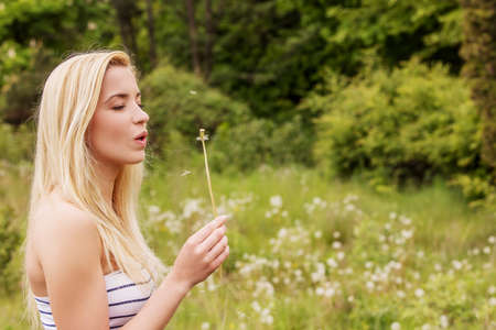 Young blonde woman posing with flowers . Outdoor shot.の写真素材