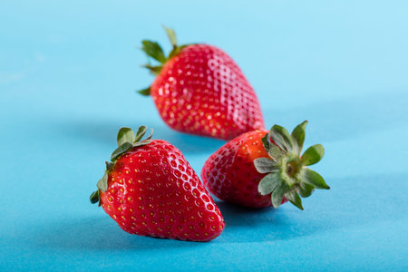 Three juicy strawberry on blue background.の写真素材