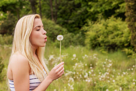 Young blonde woman posing with flowers . Outdoor shot.の写真素材