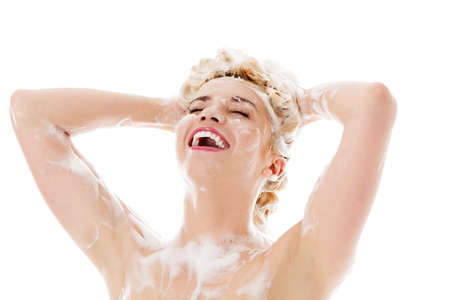 Beautiful smiling woman washing her hair with shampoo - isolated on white.の写真素材