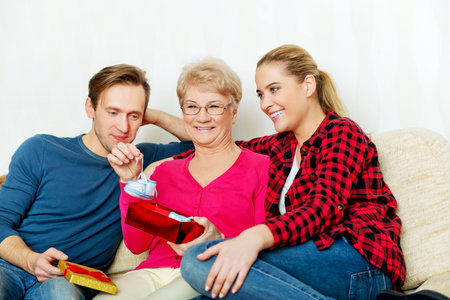 Happy family - couple with old woman who holding gift box and baby shoe.