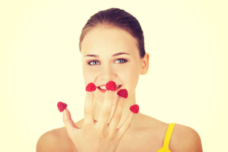 Smiling casual woman with raspberries on hand eatingの写真素材