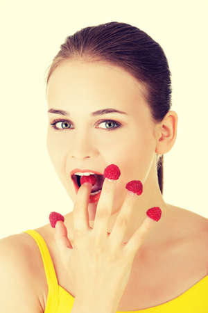 Smiling casual woman with raspberries on hand eatingの写真素材