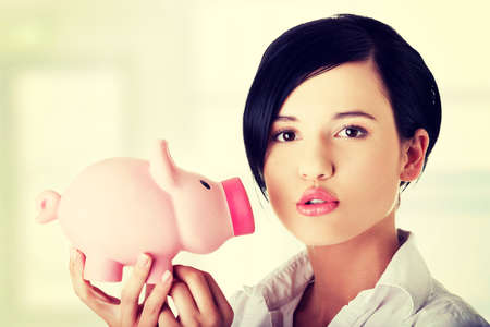 Happy business woman with her savings in piggy bankの写真素材