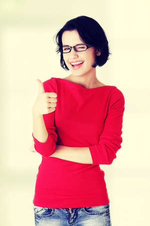 Beautiful young woman in casual clothes gesturing thumbs up.の写真素材