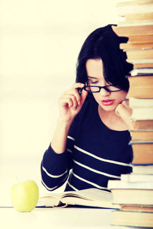 Young student woman with books studying at the desk, isolated on white backgroundの写真素材